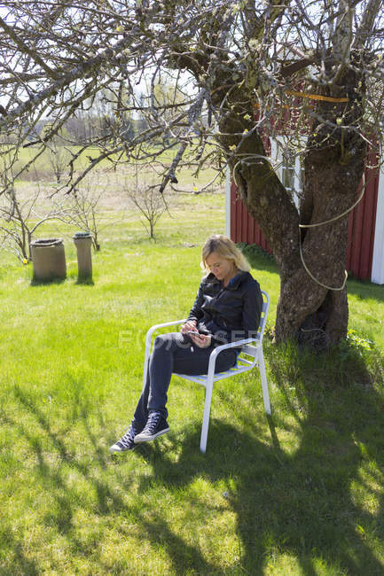 Femme assise dans le jardin par une journée ensoleillée — Photo de stock
