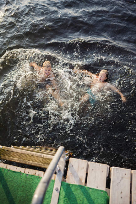 Elevated view of brother and sister swimming — Stock Photo