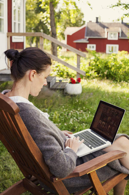 Vista lateral da mulher usando laptop, foco em primeiro plano — Fotografia de Stock