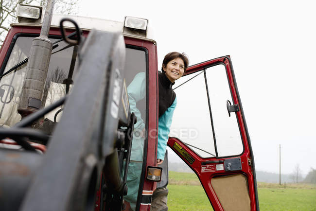 Agricultor de pé no trator e olhando para longe — Fotografia de Stock