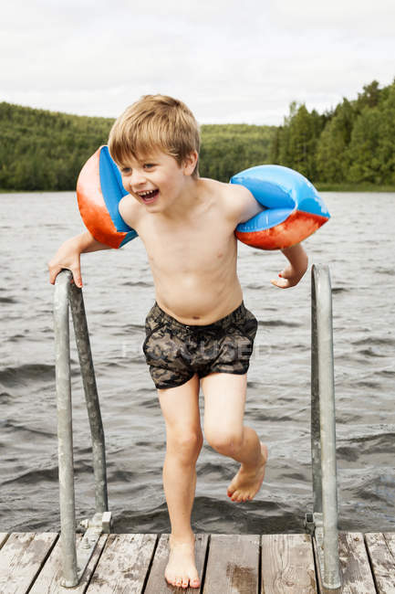 Portrait of boy with water wings on jetty — Stock Photo