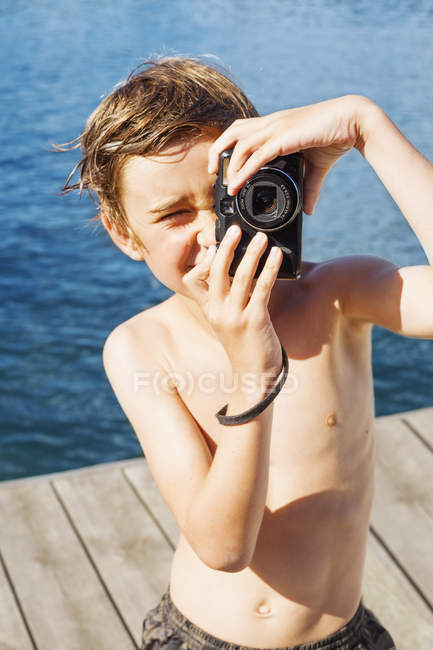 Portrait of boy photographing on jetty, selective focus — Stock Photo