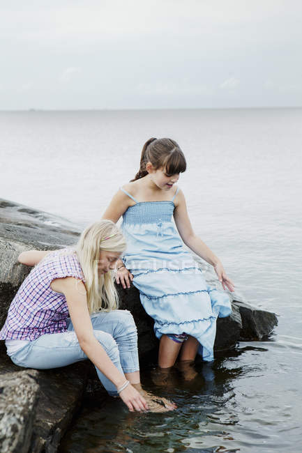 Dos chicas jugando a la orilla del mar, se centran en primer plano - foto de stock