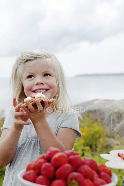 Девушка ест клубничный десерт на открытом воздухе, сосредоточиться на переднем плане — стоковое фото