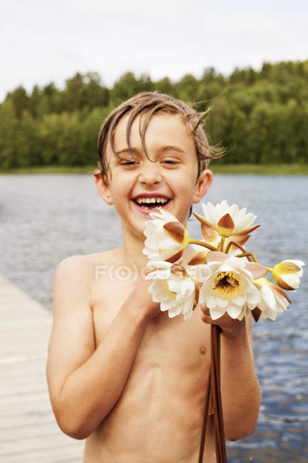 Portrait de garçon tenant des fleurs, mise au premier plan — Photo de stock