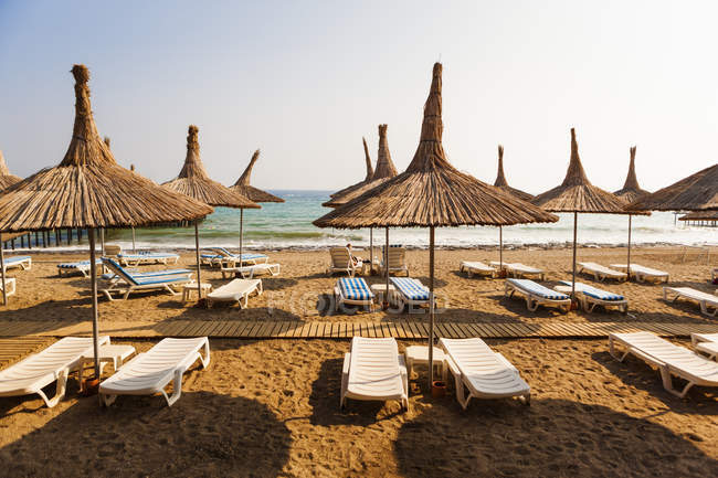 Beach with straw sunshades and deck chairs, turkey — Stock Photo