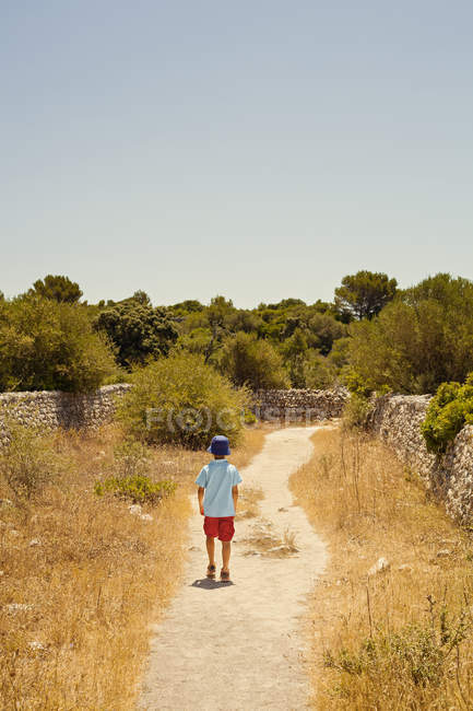 Rear view of boy walking down path — Stock Photo