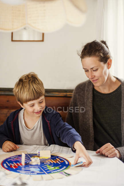Mãe e filho jogando jogo de tabuleiro na sala de estar — Fotografia de Stock