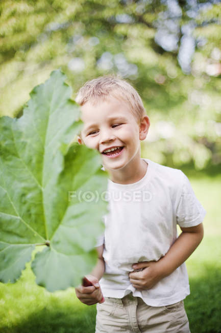 Porträt eines lachenden Jungen mit Blatt, differenzieller Fokus — Stockfoto