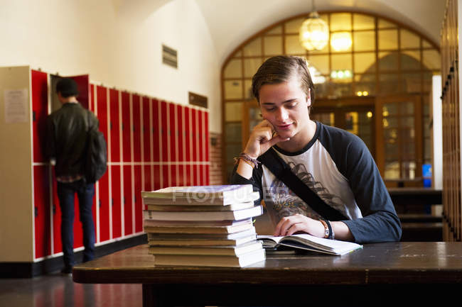 Estudiante masculino leyendo en el escritorio, se centran en primer plano - foto de stock