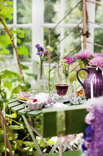 Десерт и красное вино на столе в саду — стоковое фото