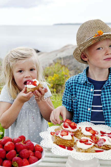 Niños comiendo postre de fresa, al aire libre - foto de stock