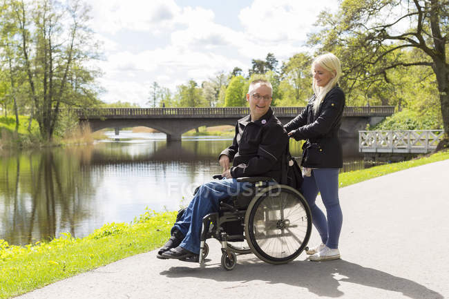 Mann im Rollstuhl mit persönlicher Assistentin im Park — Stockfoto