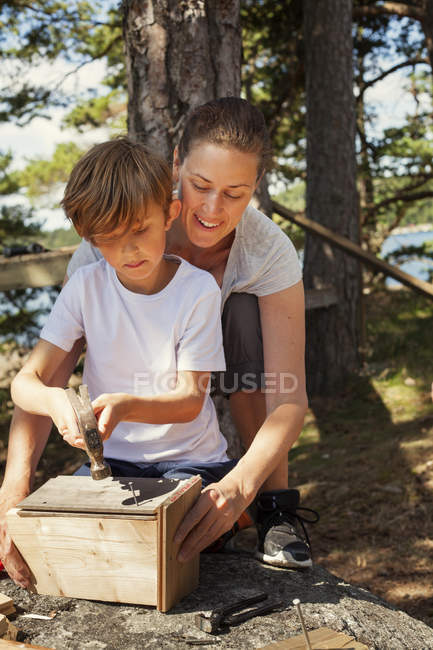 Mutter hilft Sohn beim Vogelhäuschen bauen, Fokus auf Vordergrund — Stockfoto