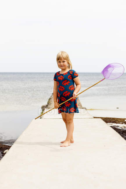 Mädchen steht mit Fischernetz auf Steg — Stockfoto