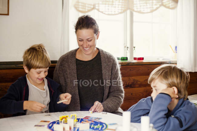 Mother and sons playing board game, focus on foreground — Stock Photo