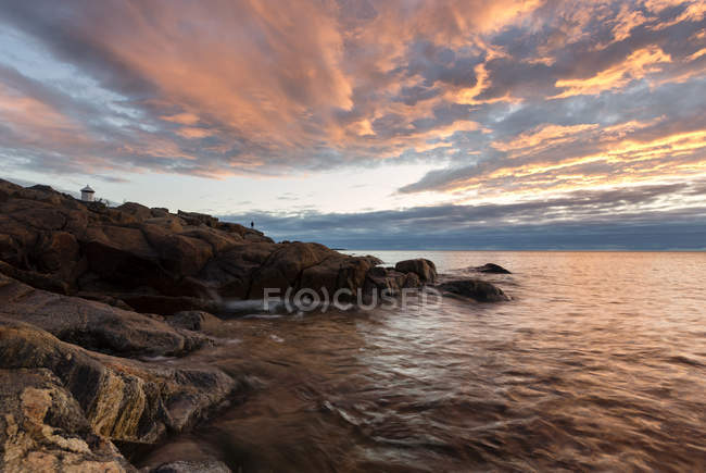 Scenic view of rocks by sea at sunset — Stock Photo