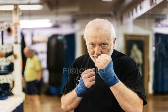 Hombre mayor con puños levantados en el entrenamiento de boxeo - foto de stock