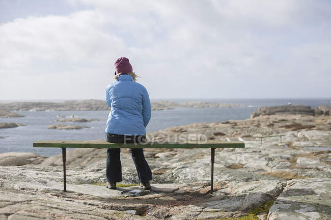 Rückansicht einer Frau, die auf einer Bank sitzt und die Aussicht betrachtet — Stockfoto
