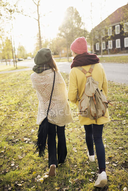Вид сзади на двух молодых женщин, идущих пешком, избирательный фокус — стоковое фото