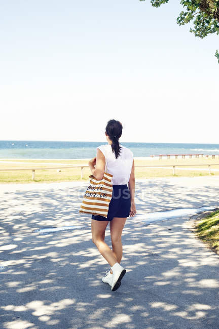 Молодая женщина с брезентовым мешком на дорожке на пляже — стоковое фото