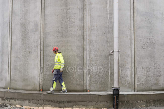 Travailleur de la construction marchant par réservoir d'eau — Photo de stock