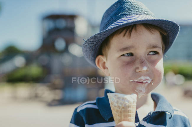 Молодий хлопчик їсть морозиво, зосередьтеся на передньому плані — стокове фото