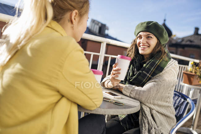 Dos mujeres jóvenes sentadas al aire libre con café - foto de stock