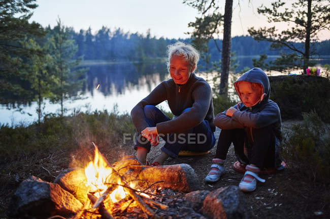 Mother and daughter by a campfire, selective focus — Stock Photo