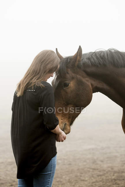 Mulher adulta média alimentando cavalo, foco seletivo — Fotografia de Stock