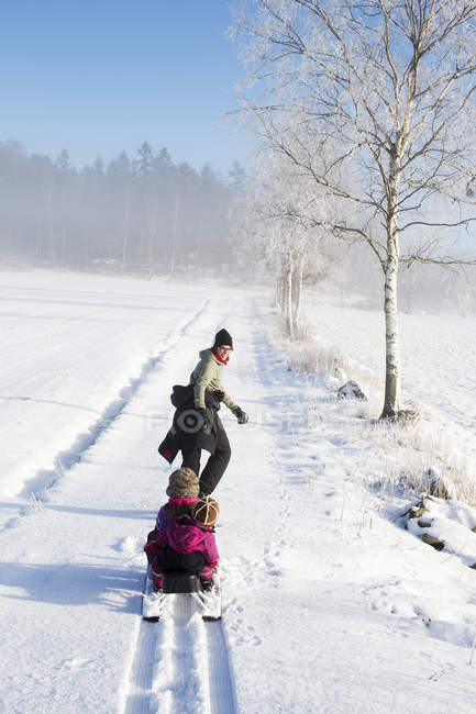 Mother pulling two young daughters on sled — Stock Photo