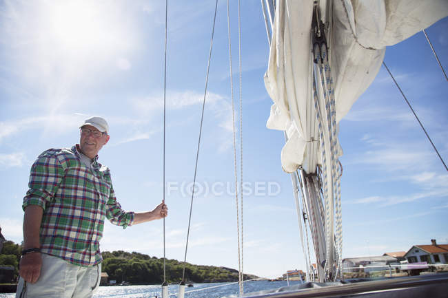 Mature man standing on deck of sailboat — Stock Photo