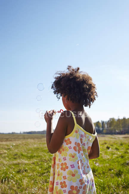 Menina soprando bolhas de sabão, foco diferencial — Fotografia de Stock