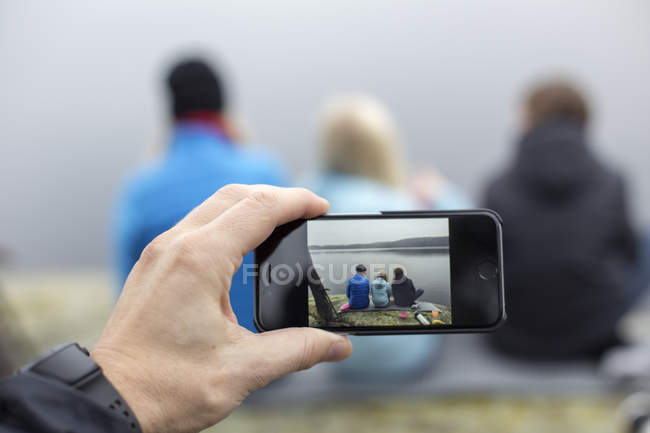 Man taking picture on smartphone of woman with son and daughter — Stock Photo