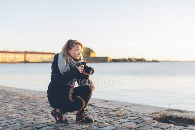 Женщина держит камеру по морю, сфокусируйтесь на переднем плане — стоковое фото