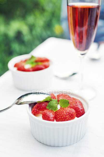 Désert de fraises dans des bols avec verre de vin sur la table, mise au point sélective — Photo de stock