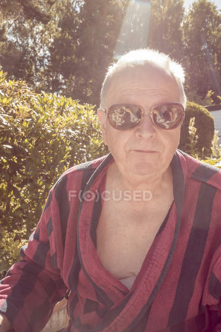 Portrait of senior man wearing striped bathrobe and sunglasses — Stock Photo