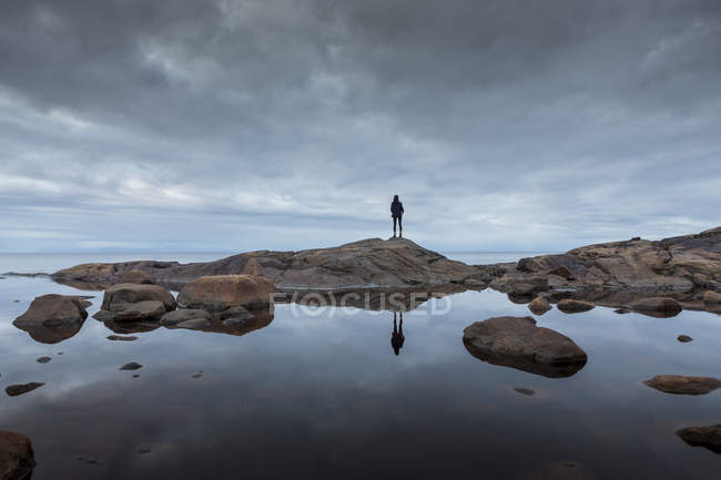 Жінка стоїть на каменях біля озера — стокове фото