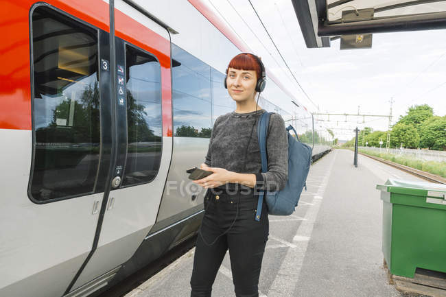 Woman wearing headphones on train platform — Stock Photo