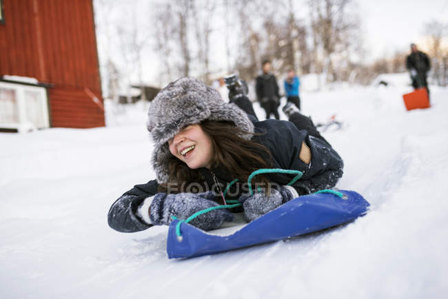 Jovem mulher deslizando em toboggan no inverno — Fotografia de Stock