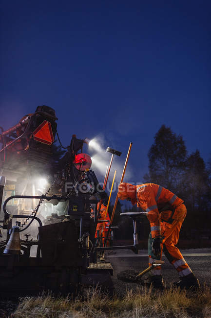 Three manual workers repairing road — Stock Photo