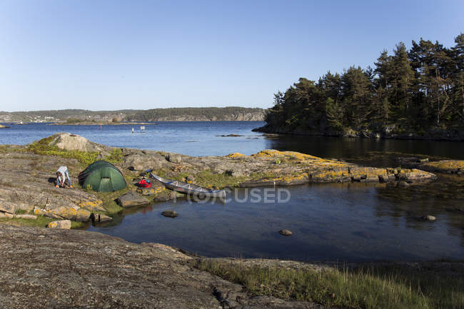 Man camping on riverbank under blue sky — Stock Photo