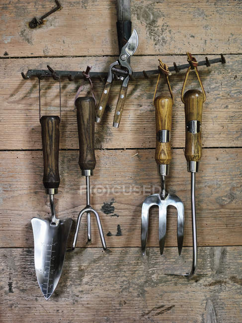 Primer plano de herramientas de jardín en la pared de madera - foto de stock