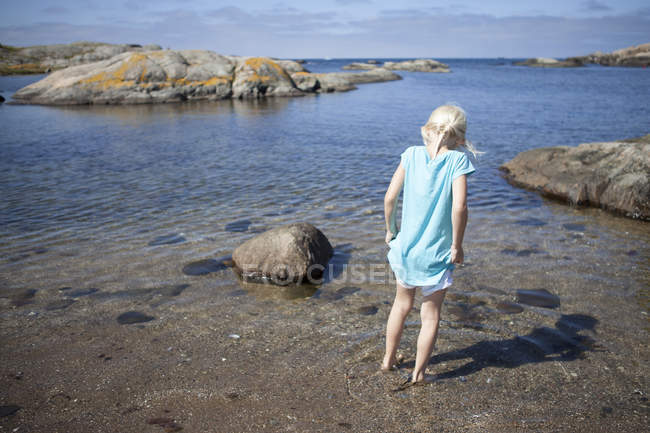 Вид сзади девушки, стоящей на лодыжке глубоко в воде — стоковое фото