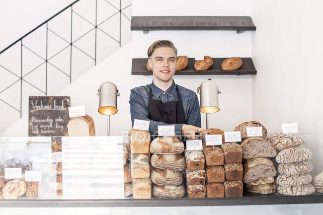 Усміхнений працівник пекарні дивиться на камеру — стокове фото