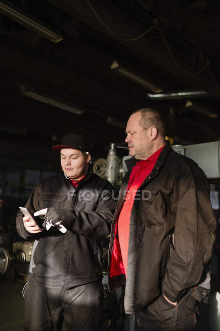 Man and teenage boy using phone, focus on foreground — Stock Photo