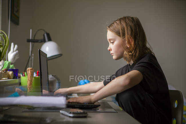 Niño usando el ordenador portátil en el escritorio, enfoque selectivo - foto de stock