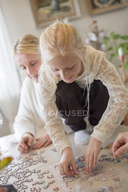 Девушка делает головоломки, сосредоточиться на переднем плане — стоковое фото