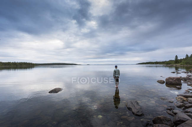 Rückansicht eines Mannes, der auf Felsen am See steht — Stockfoto