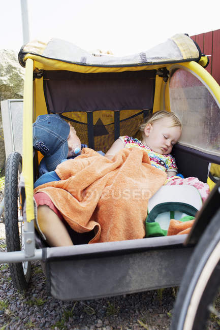 Two children sleeping in bicycle trailer, selective focus — Stock Photo